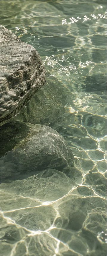 Sunlight moving across green water and rocks